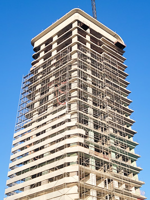 A beige building with scaffolding against a blue sky.