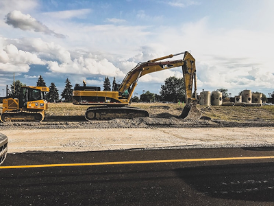 An excavator picking up dirt on a street construction site.